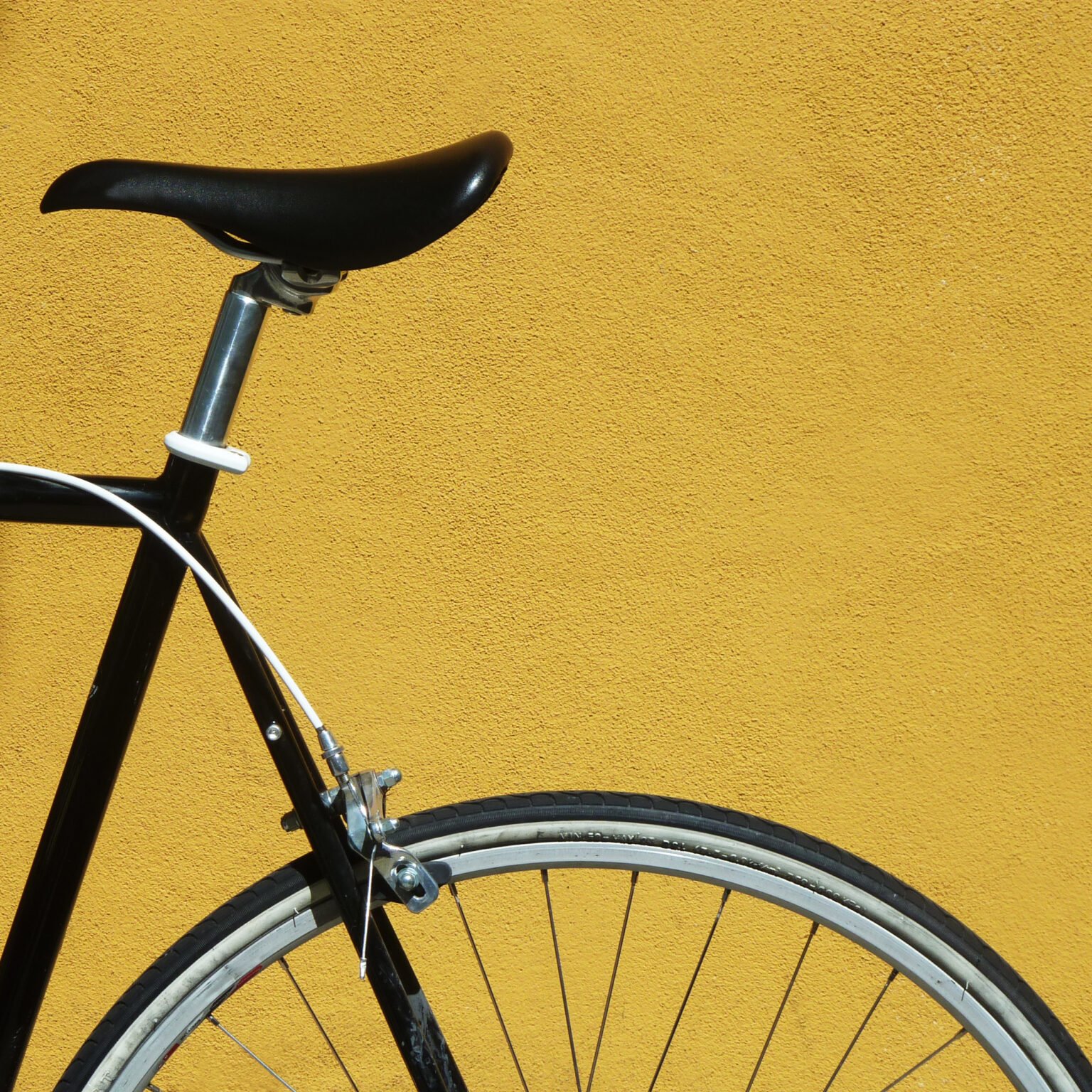 Detail of a black bicycle against a yellow wall