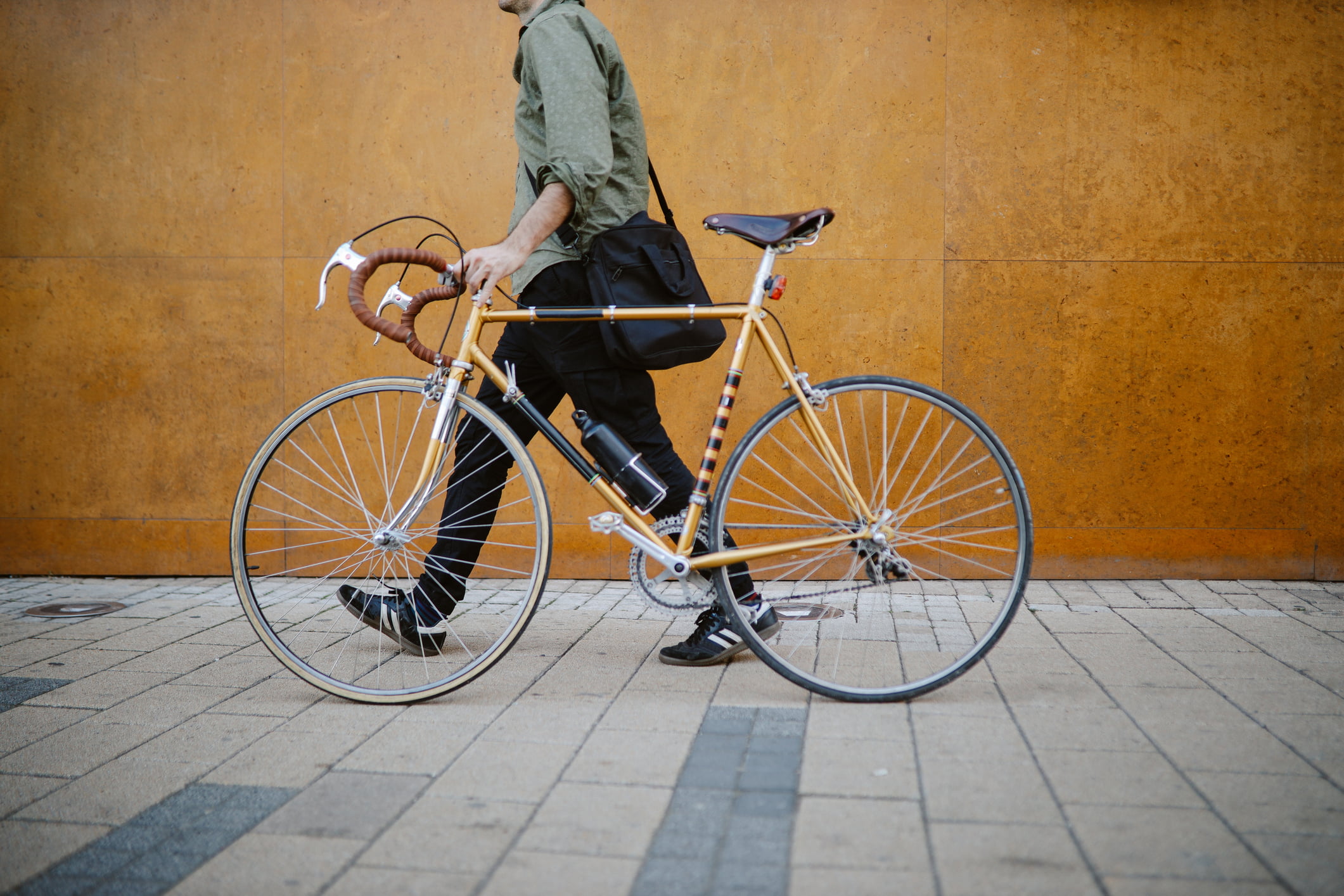 Commuter pushing his vintage road bicycle on the pavement, getting to work.